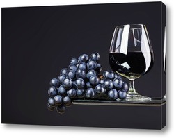    Бокал вина и виноград на темном фоне